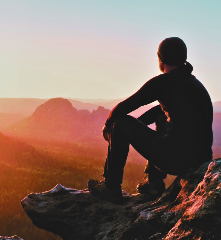 Man on mountaintop looking at sunrise